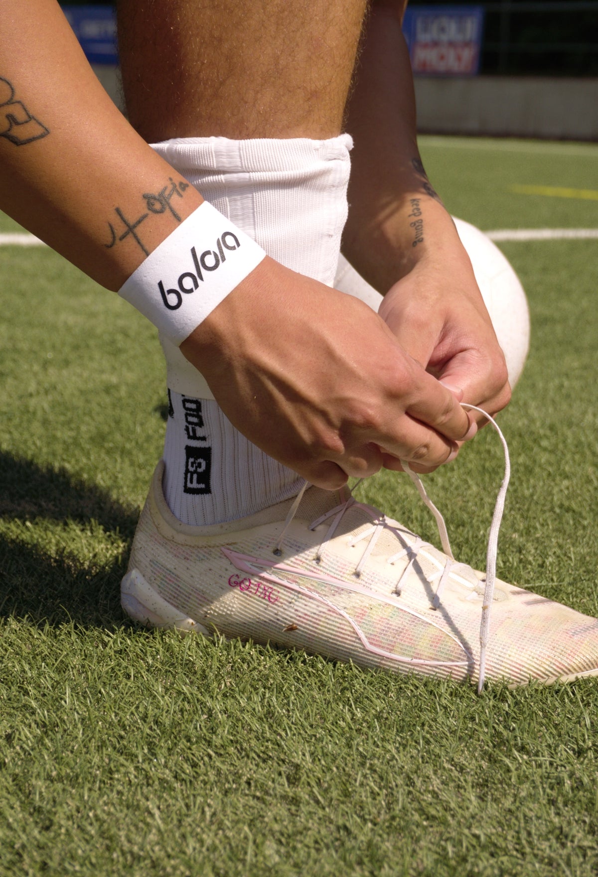 Nahaufnahme eines Spielers, der die Schnürsenkel eines Fußballschuhs bindet. Er trägt das weiße Ligora-Fussball-tape mit dem Balora-Logo am Handgelenk.