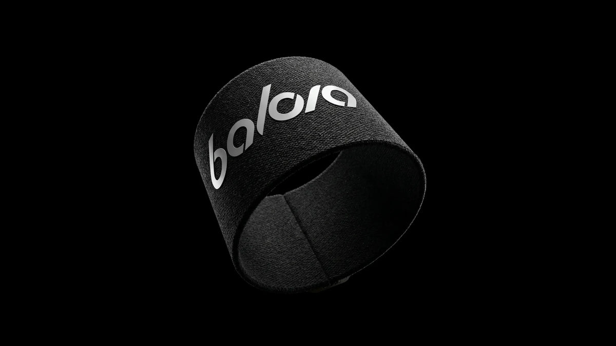 Ein schwarzes, elastisches Fussball-tape-Band von Balora Ligora, schräg positioniert auf weißem Hintergrund, mit einem silbernen, reflektierenden 'balora'-Logo-Aufdruck. Die gewebte Textur des Materials ist deutlich sichtbar.